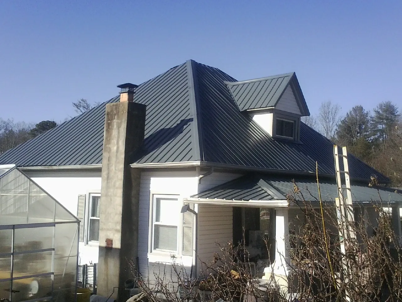 Dark blue standing seam metal roof on a white farmhouse with dormer — Slate & Tile Roof Repair by Roofing Brothers in Mayfield