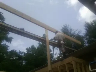 Carpenter setting a ridge beam over a new addition frame — Ice Dam Removal by Roofing Brothers in Mayfield