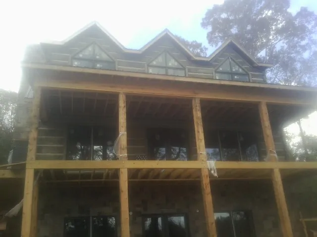 Dormers and porch framing on a large log home under construction — Roof Coating work by our crew in Mayfield