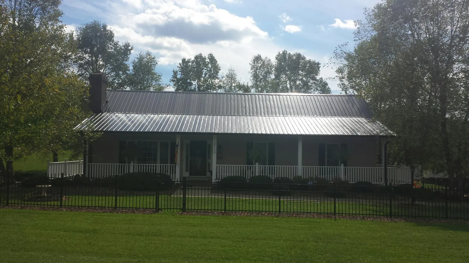 Gray metal roof on a brick ranch with a full width front porch — Gutter Guard Installation work by our crew in Mayfield
