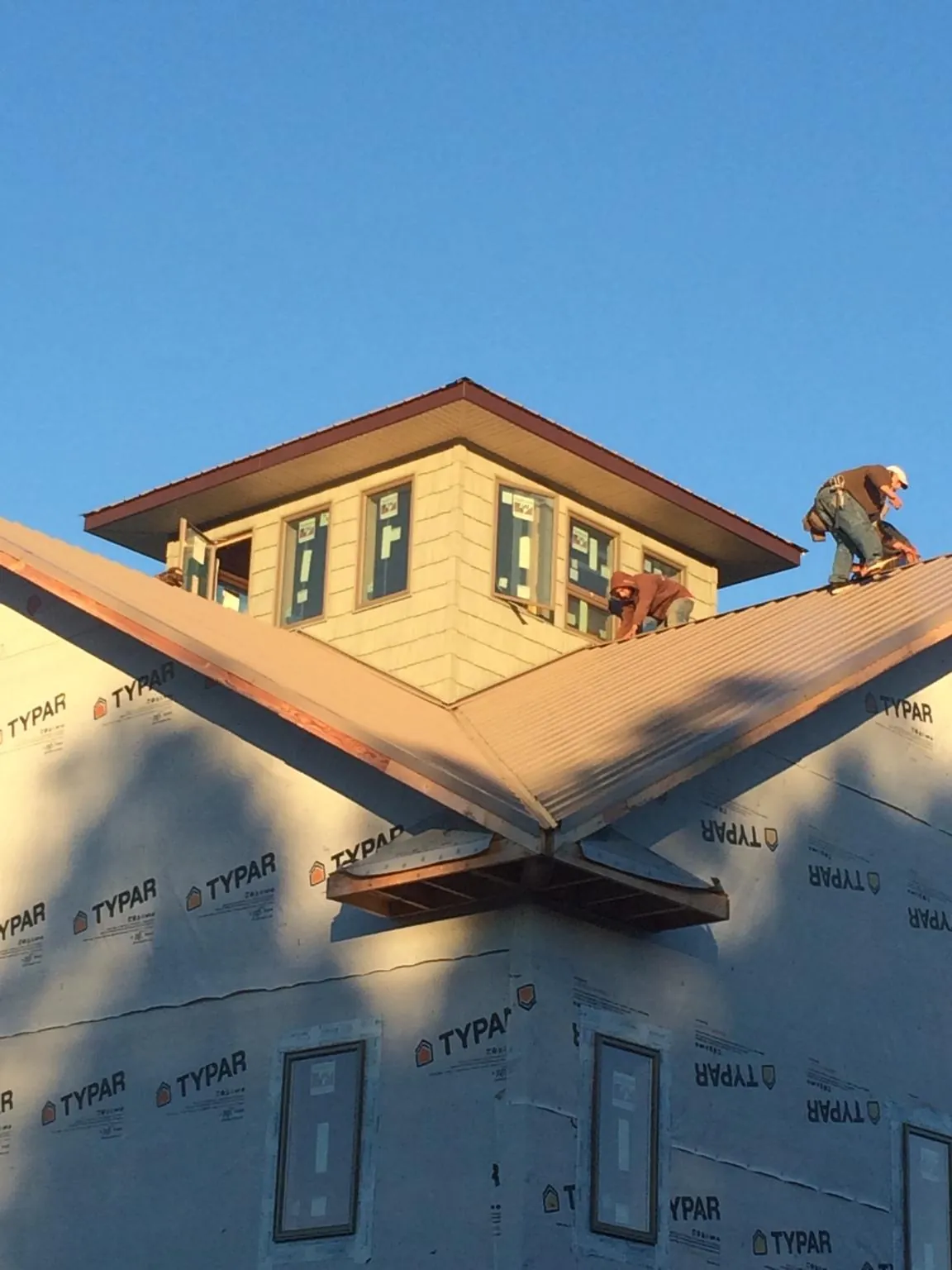 Roofers working around a rooftop cupola on a new metal roof at sunset — Roof Waterproofing in Mayfield by Roofing Brothers